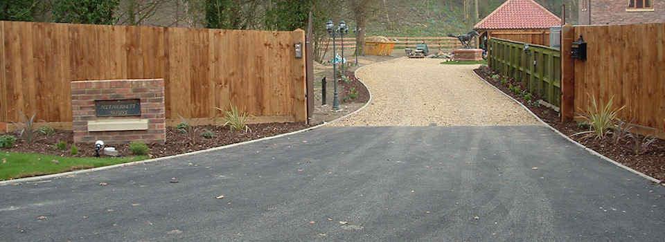 Asphalt drive entrance with kerbstone edging and shingle drive, fencing, turf, garden lighting and landscaping Asphalt drive entrance with kerbstone edging and shingle drive, fencing, turf, garden lighting and landscaping
